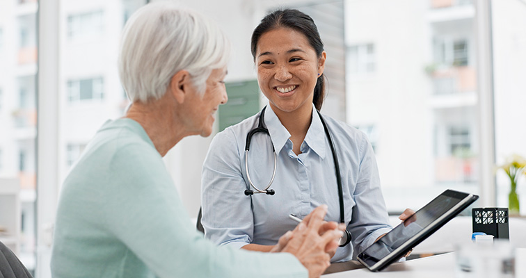 Doctor talking to old patient while showing ipad